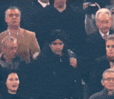 a group of people are sitting in a stadium and one of them is wearing a black jacket