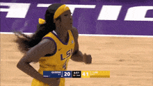 a female basketball player wearing a lsu jersey is running on the court