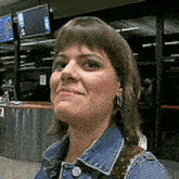 a woman in a denim jacket is smiling in front of a counter