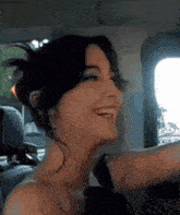 a woman is smiling while driving a car