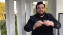 a man with a beard is wearing a suit and making a heart shape with his hands