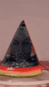 a cat is looking at a watermelon with a picture of a man in it .