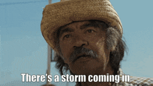 a man wearing a straw hat and a plaid shirt says there 's a storm coming in