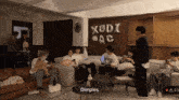 a group of people are gathered in a living room with a balloon that says xodi ac