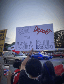 a person holds up a sign that says " don t deport the latina baddies "
