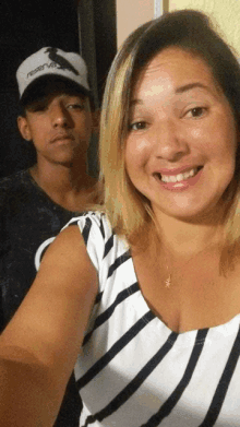 a woman wearing a striped shirt is smiling next to a boy wearing a hat that says reserva