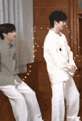 a couple of young men are standing next to each other in a room and dancing .
