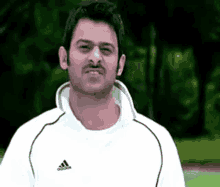 a man wearing a white adidas shirt is making a face