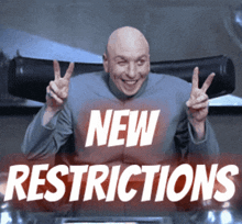 a bald man is giving a peace sign in front of a sign that says " new restrictions "