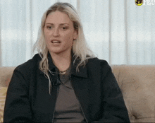 a woman wearing a black jacket is sitting on a couch and talking