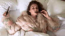 a woman in a fur coat is laying in bed eating chocolate