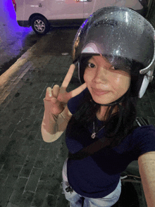 a woman wearing a helmet gives the peace sign