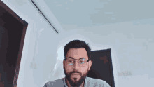 a man with a beard wearing glasses looks at the camera
