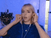 a woman in a blue shirt is wearing headphones and making a funny face