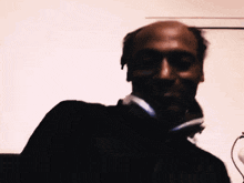 a bald man with headphones around his neck
