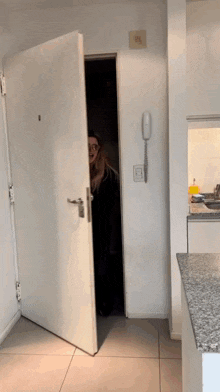 a woman peeking out from behind a door in a room