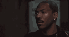 a man is talking on a cell phone in a dark room while wearing earrings .