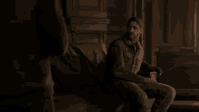 a man is sitting on a couch in a dark room talking to another man .