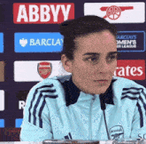 a woman sitting in front of an ad for abbyy barclays and emirates