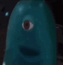 a blue monster with a red eye is looking at the camera in a blurry photo .