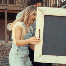 a man and a woman are holding a picture frame together