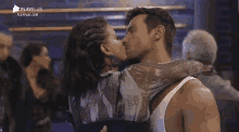 a man and a woman are hugging and kissing in front of a playplus logo