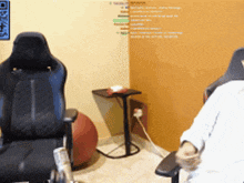 a man in a wheelchair sits in a chair in front of a wall that has a qr code on it