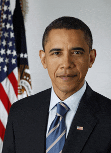 a man in a suit and tie stands in front of the american flag
