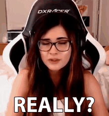 a woman wearing glasses and headphones is sitting in a dxracer gaming chair