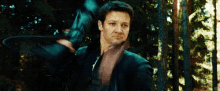 a man is standing in the woods holding a sword .