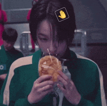 a woman in a green jacket is eating a sandwich with a yellow hand on her head