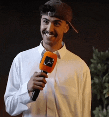 a man wearing a hat is smiling while holding a microphone