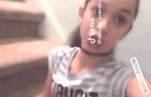 a young girl is taking a selfie in front of stairs .