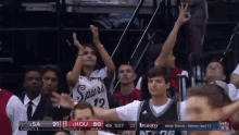 a woman wearing a spurs jersey applauds during a game