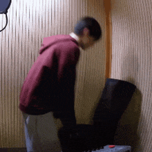 a man in a maroon hoodie is standing in a room