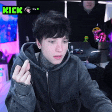a young man in a hoodie is giving the middle finger in front of a screen that says kick