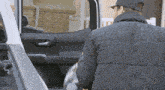 a man in a black jacket is loading something into the back of a white truck