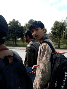 a man wearing a black adidas bag is standing next to a boy