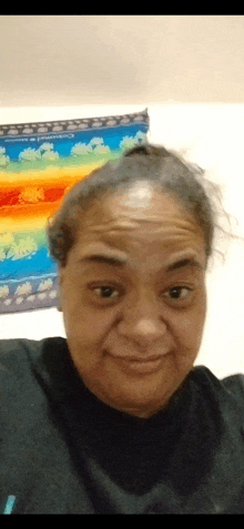 a woman is making a funny face in front of a rainbow tapestry