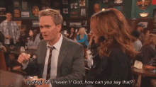 a man in a suit and tie is talking to a woman in a crowded bar