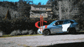 a silver suv is parked in front of a house with the letter g in red