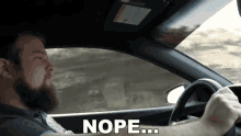 a man with a beard is driving a car and the word nope is on the bottom