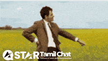 a man in a suit and tie is standing in a field with a star tamil chat logo behind him