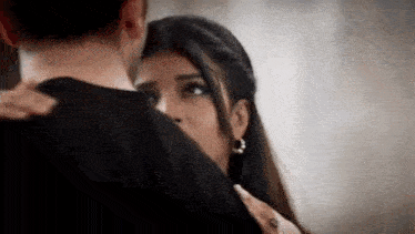 a man and a woman are hugging each other and the woman is covering her face with her hand .