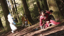 a man in a red coat is kneeling in the woods