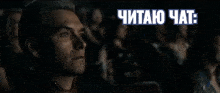 a man sitting in a dark room with the words " читаю чат " written above him
