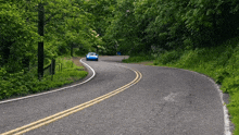 a blue car driving down a curvy road