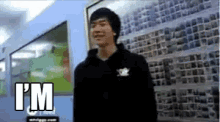 a man in a black hoodie is standing in front of a wall that says i 'm on it