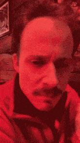 a close up of a man 's face with a red background .