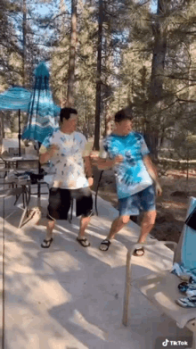 two men are standing on a patio holding drinks .